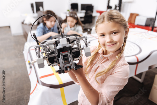 Cute little girl demonstrating robot at school photo