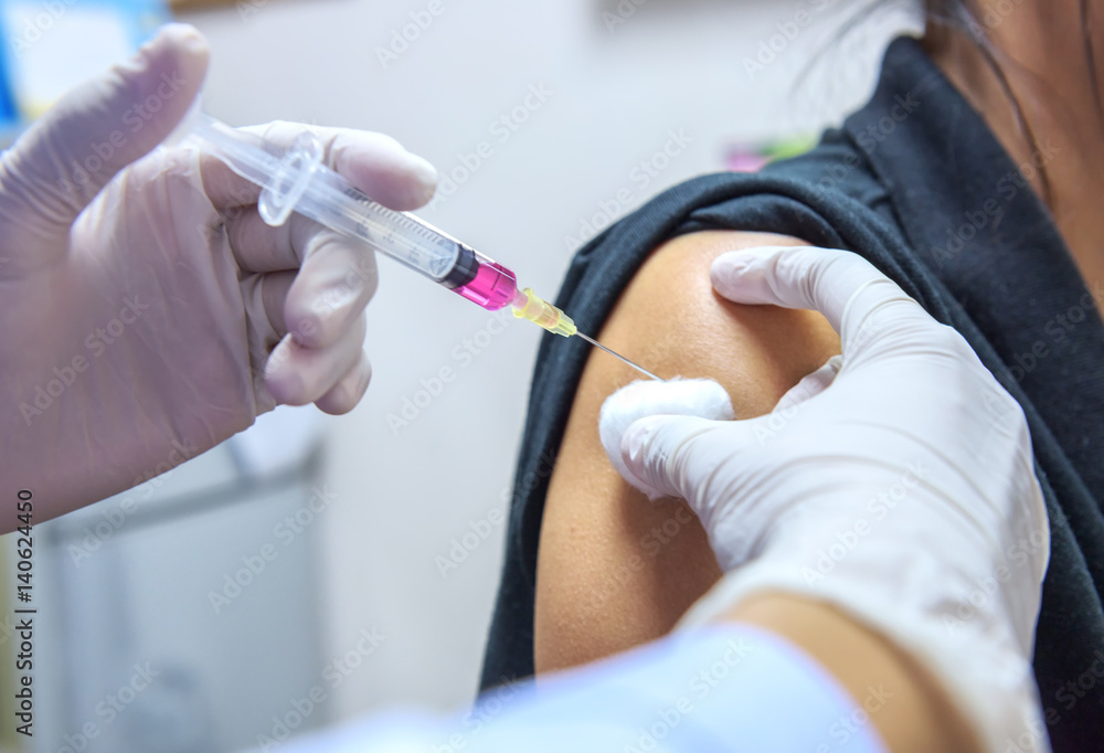Close-up hands,nurses are vaccinations to patients using the syringe.Doctor vaccinating women in hospital.Are treated by the use of sterile injectable upper arm. injection Close-up hands,nurses are vaccinations to patients using the syringe.Doctor vaccinating women in hospital.Are treated by the use of sterile injectable upper arm. injection