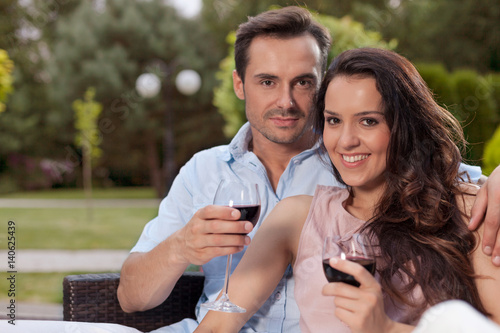 Portrait of beautiful young couple having red wine in park