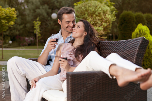 Romantic young holding wine glasses on easy chair in park