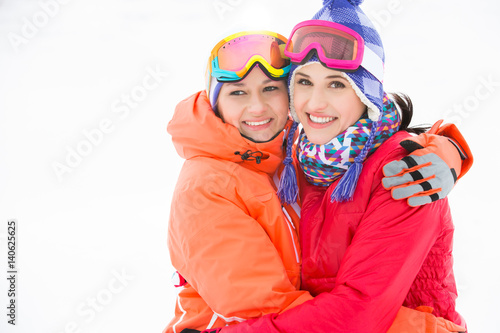Portrait of happy young women in warm clothing embracing outdoors