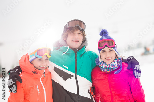 Happy young man with female friends standing arm around in snow
