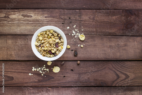 Granola cereal flakes with dried fruit on a wooden desk
