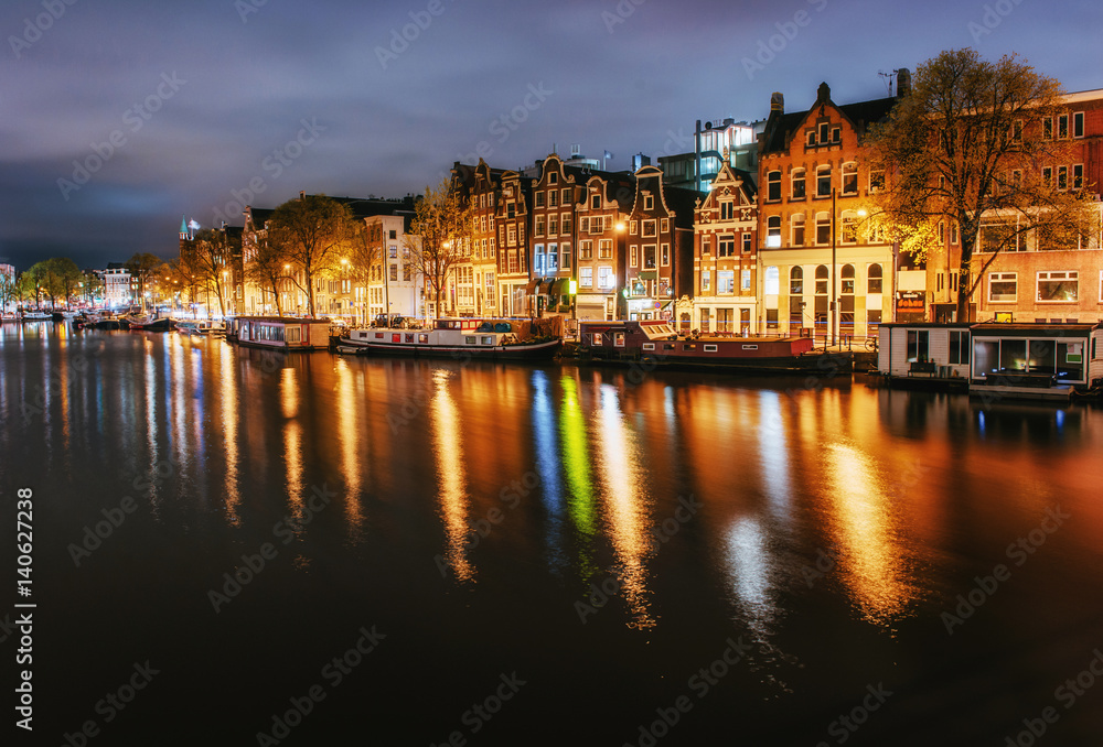 Night city view of Amsterdam canal, typical dutch houses and boa