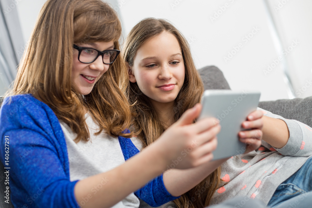 Sisters using digital tablet together at home Sisters using digital tablet together at home