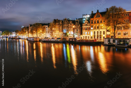 Night city view of Amsterdam canal, typical dutch houses and boa