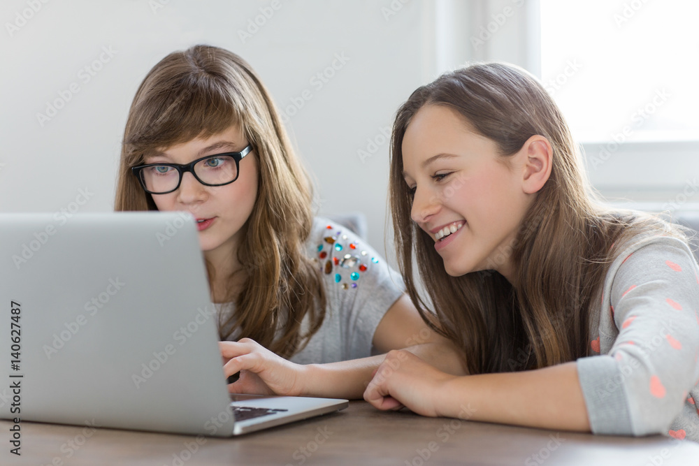 Sisters using laptop together at home Sisters using laptop together at home