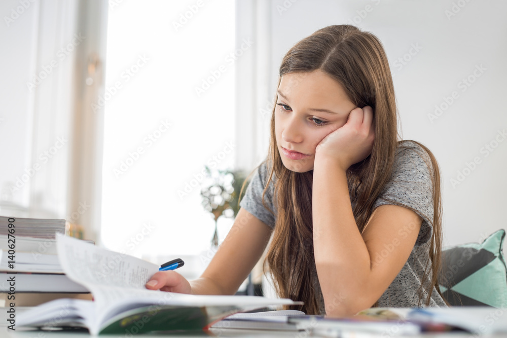 Bored girl studying at table in house Bored girl studying at table in house