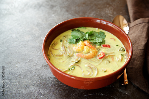 Spicy soup with coconut milk, noodles and shrimps. Eastern cuisine 