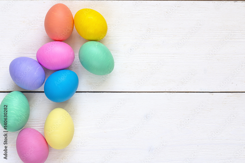 Colored Easter eggs on white wooden background.