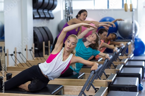 trainer assisting group of women with stretching exercise