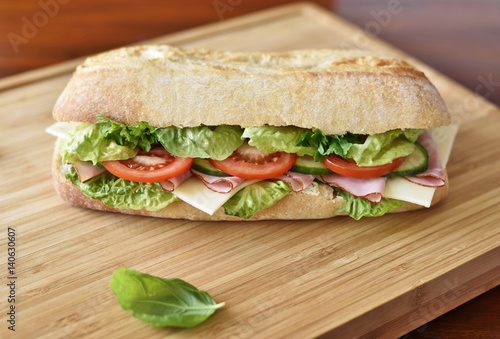 Delicious ciabatta sandwich with ham, tomatoes, fresh salad and cucumber slices.