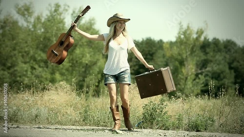Young woman with guitar on the road and her vintage baggage 