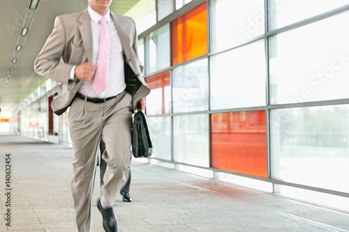 Midsection of businessmen rushing on railroad platform © moodboard