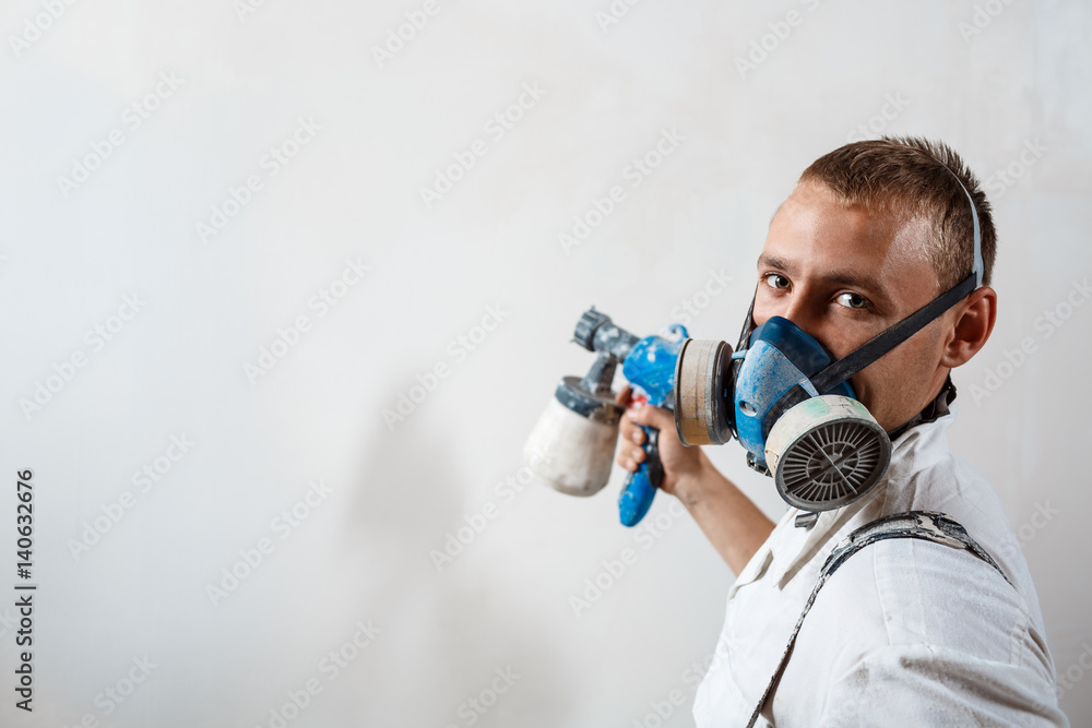 Worker painting wall with spray gun in white color. Worker painting wall with spray gun in white color.