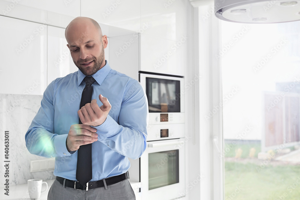 Mid adult businessman buttoning sleeve at home