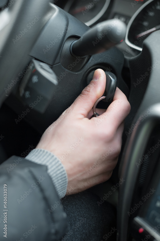 Closeup inside vehicle of hand holding key in ignition, start engine key