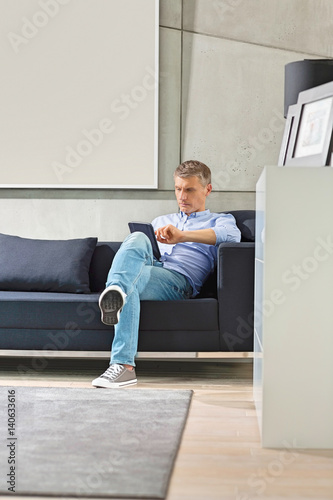 Full-length of Middle-aged man using tablet PC on sofa © moodboard