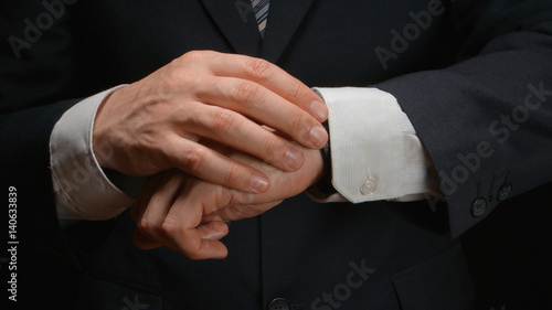Businessman looks time on a wrist watch
