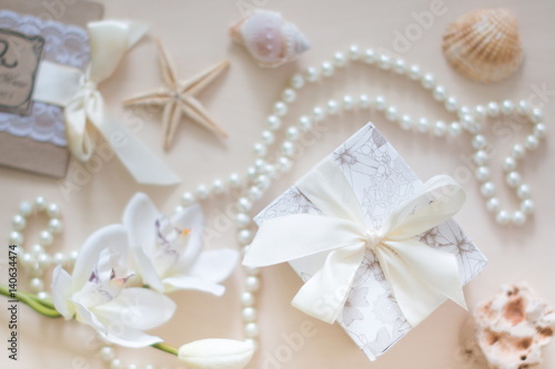 Present, beads, seashells, orchid on wooden background