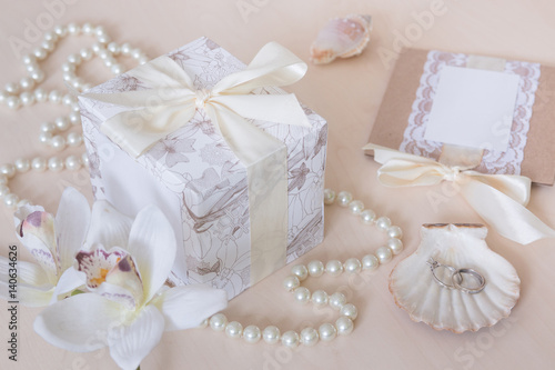 Present, beads, seashells, orchid and rings on wooden background