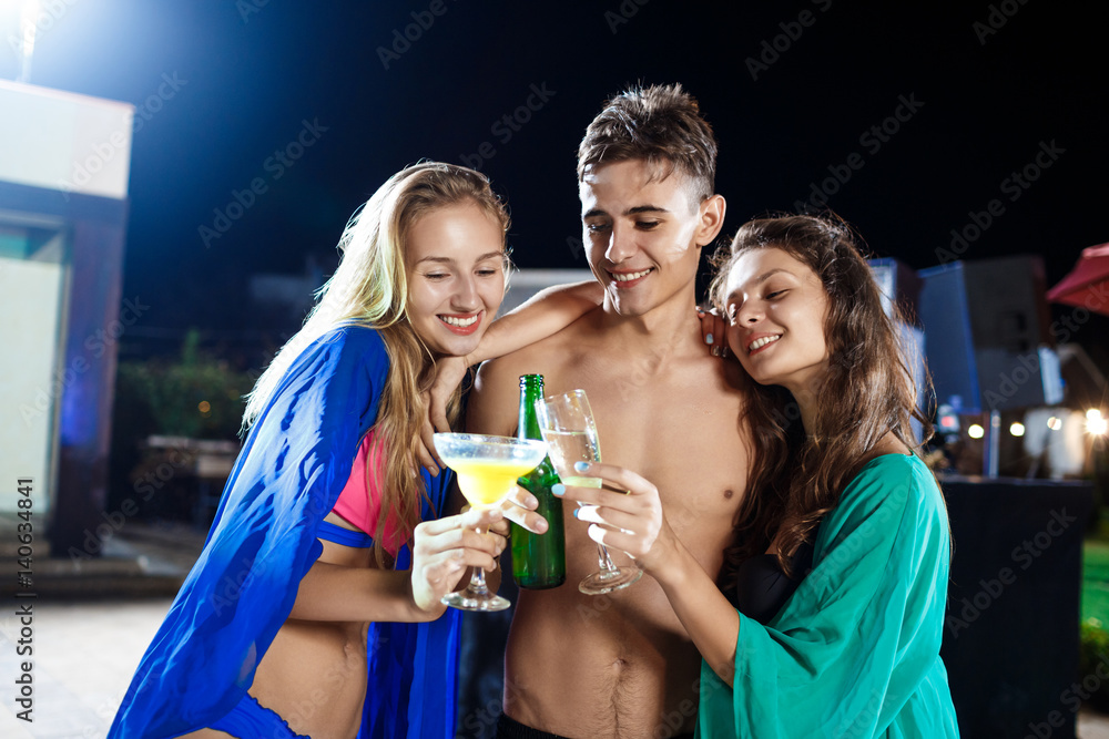 Cheerful friends smiling, rejoicing, resting at party near swimming pool.