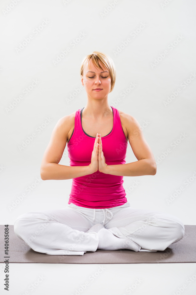 Woman exercising yoga indoor,Lotus position/Padmasana Woman exercising yoga indoor,Lotus position/Padmasana