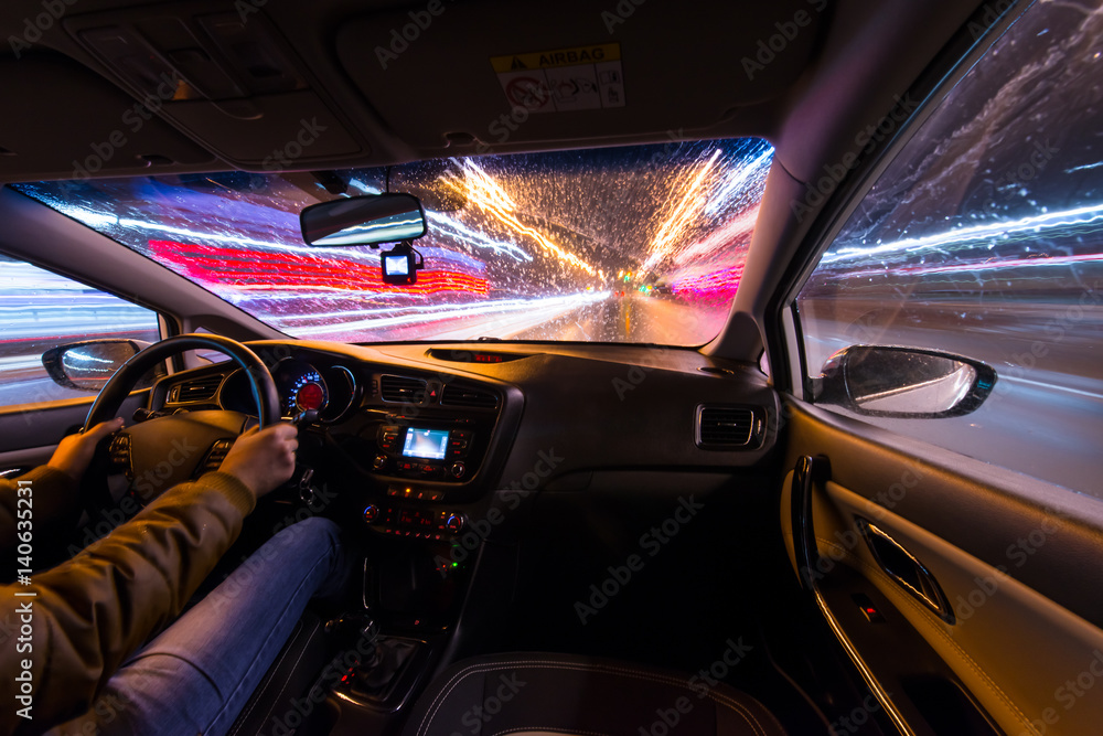 Night road view from inside car natural light street and other cars is motion blurred, during a rain