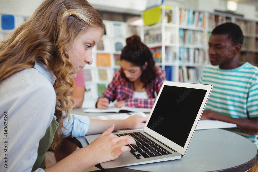 schoolgirl using laptop with her classmates schoolgirl using laptop with her classmates