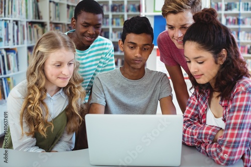 Attentive classmates using laptop in library