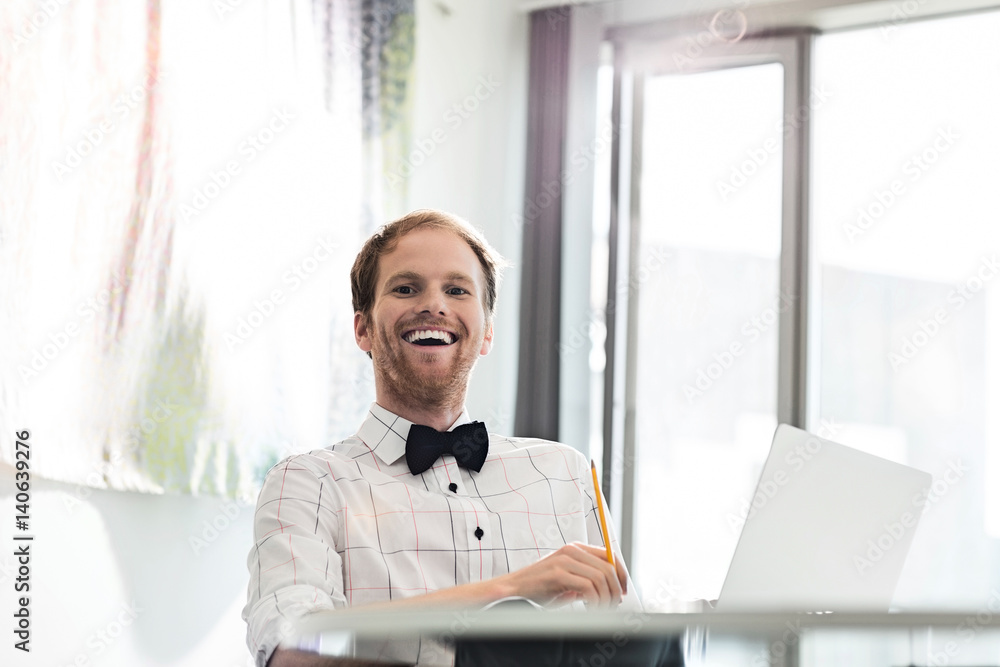 Fototapeta premium Cheerful businessman sitting at desk in creative office