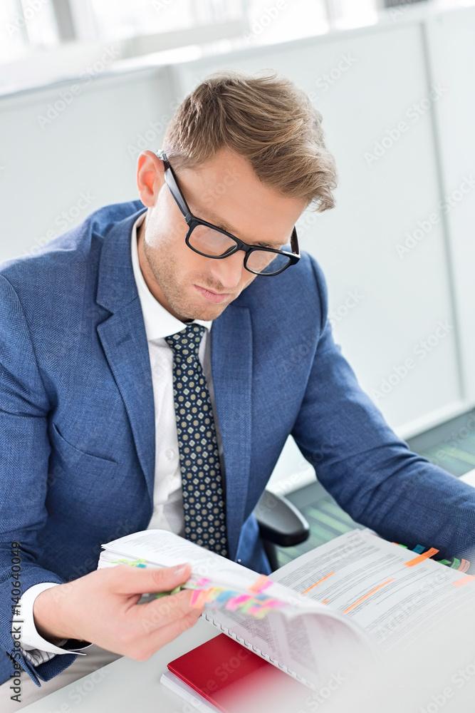 Businessman reading file at desk in creative office Businessman reading file at desk in creative office