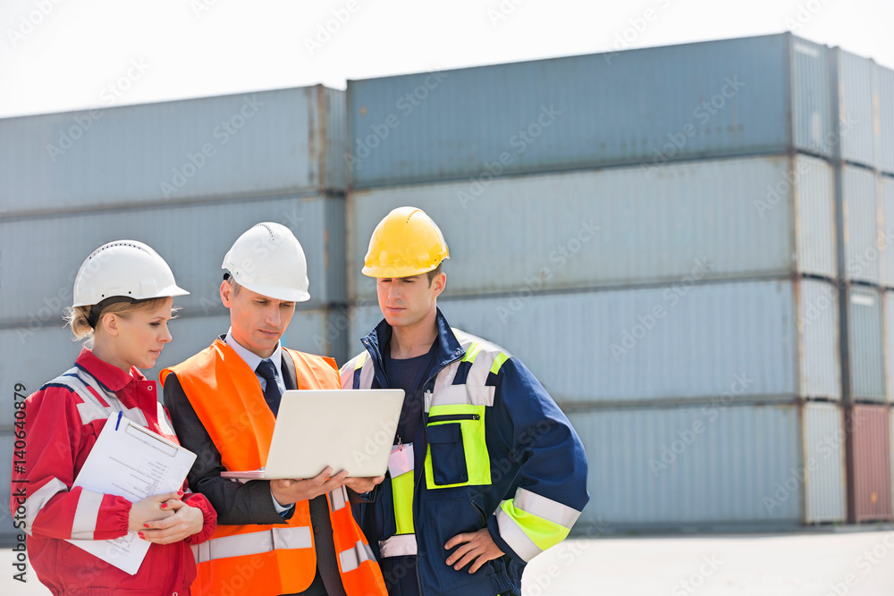 Workers discussing over laptop in shipping yard Workers discussing over laptop in shipping yard