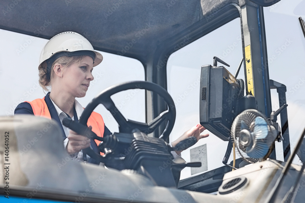 Female worker operating forklift truck in shipping yard Female worker operating forklift truck in shipping yard