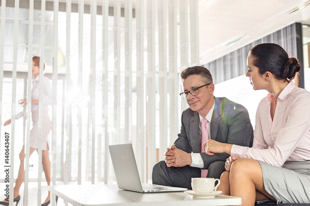 Businessman and businesswoman discussing in office Businessman and businesswoman discussing in office