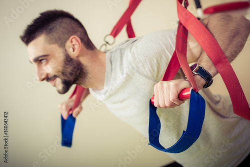 Fit man doing push ups training arms with fitness straps