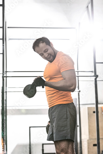 Confident man lifting kettlebell in crossfit gym