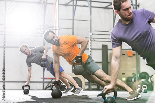 Men exercising with kettlebells in crossfit gym