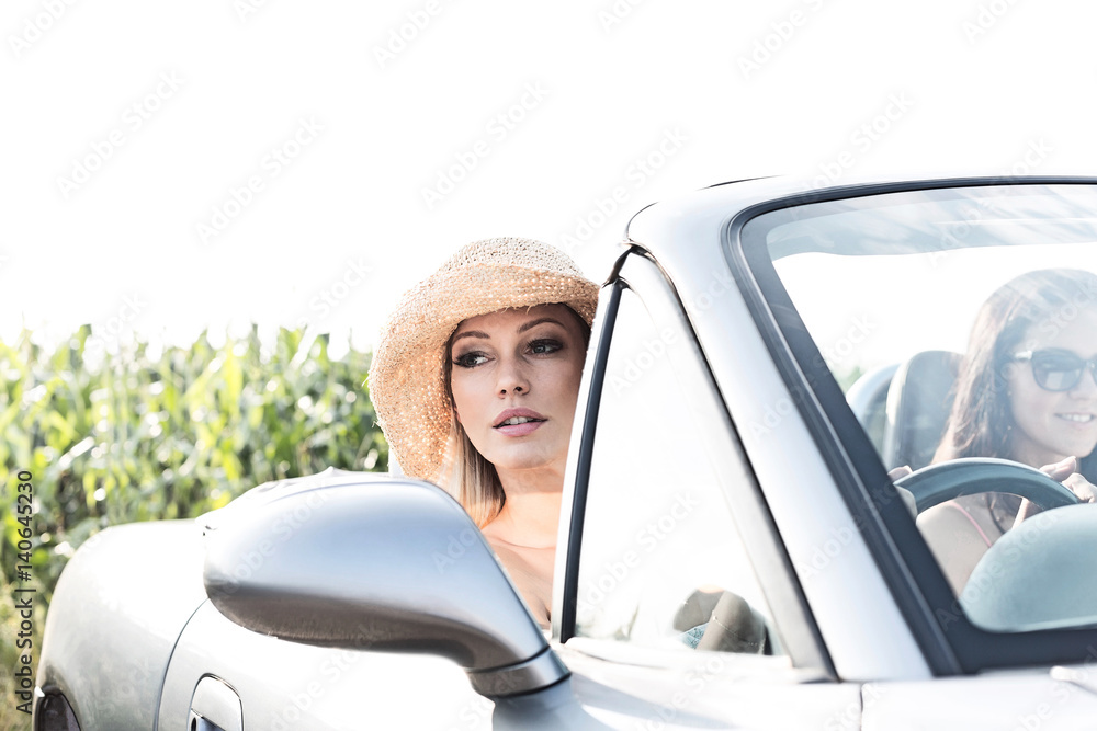 Woman sitting in convertible with female friend on sunny day Woman sitting in convertible with female friend on sunny day