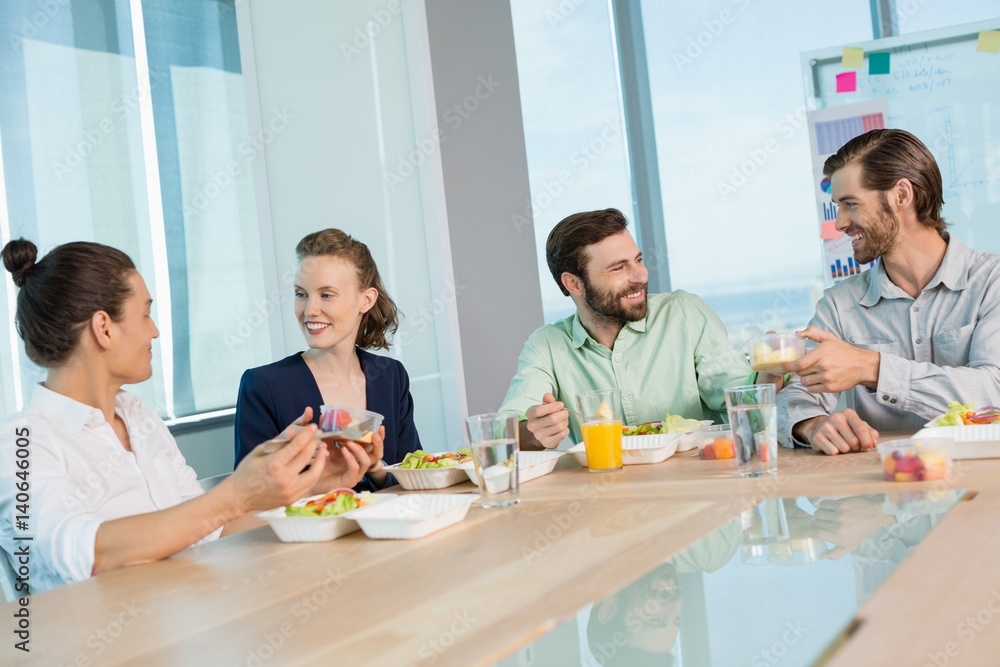 Smiling business executives having meal in office Smiling business executives having meal in office