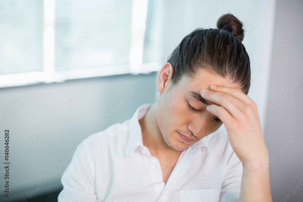 Tense business executive sitting with hand on forehead Tense business executive sitting with hand on forehead