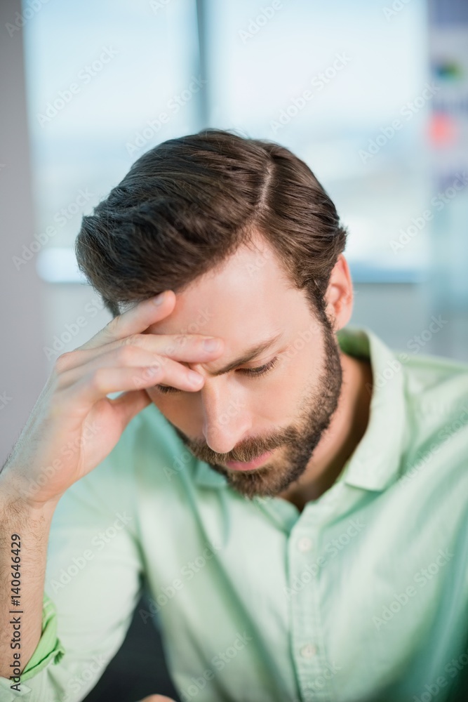 Tense business executive sitting with hand on forehead Tense business executive sitting with hand on forehead