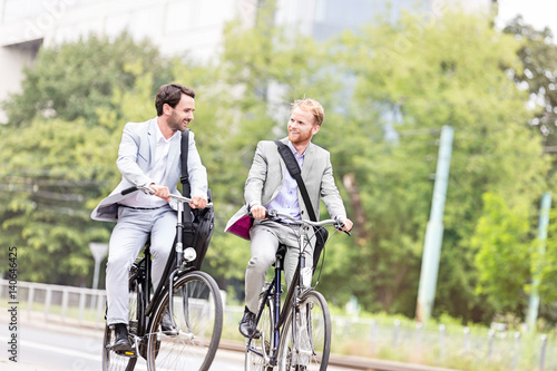 Businessmen talking while cycling outdoors