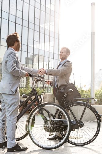 Businessmen shaking hands outside office building