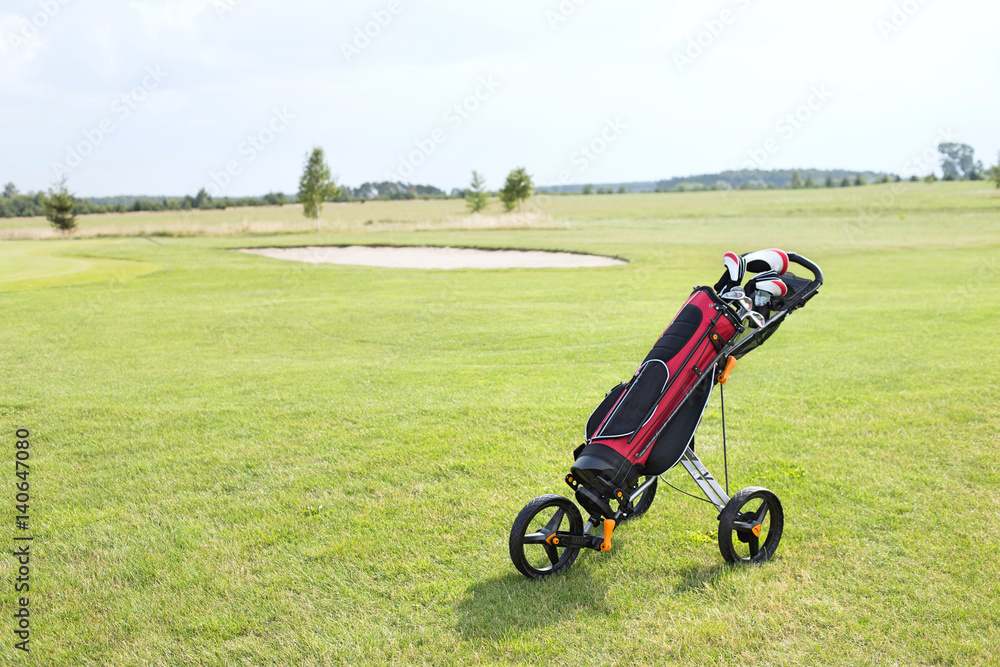 Fototapeta premium Golf club bag on pushcart at golf course against sky