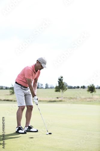 Full-length of middle-aged man playing golf at course