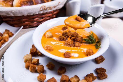 A plate of pumpkin cream soup with croutons and dill. photo