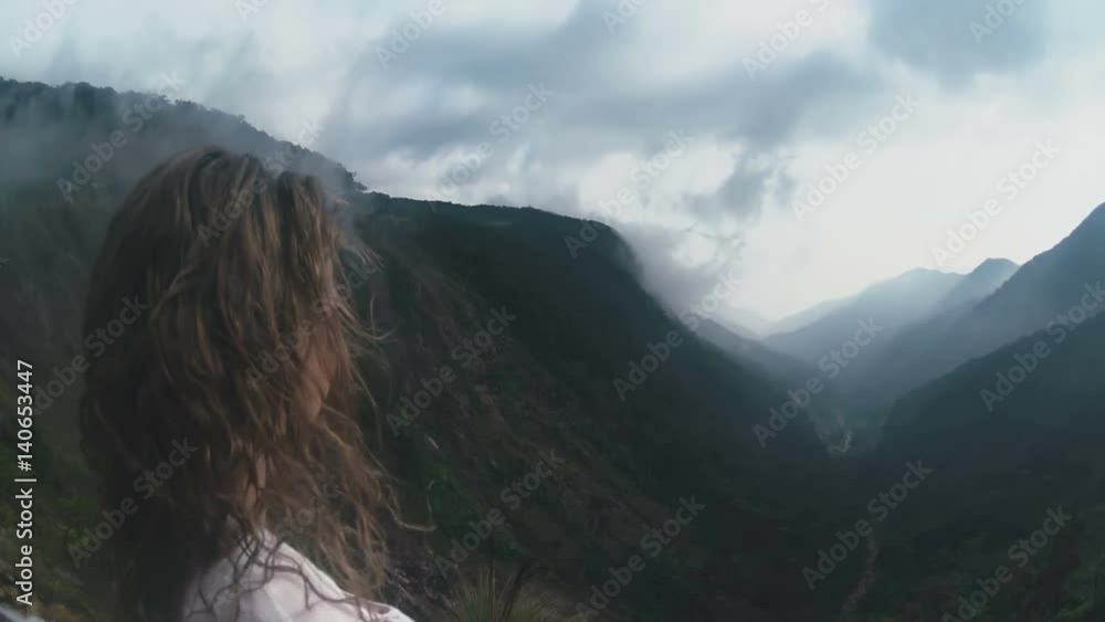 Curly woman standing at the cliff of mount close-up Curly woman standing at the cliff of mount close-up