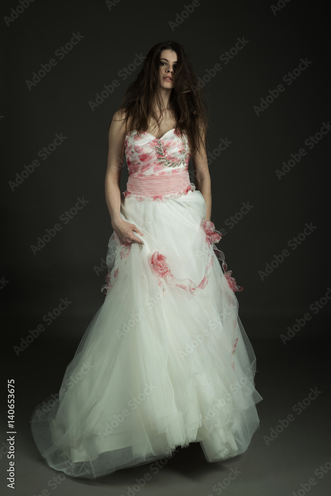 Bellissima modella in studio posa con vestito bianco da matrimonio con fiori Bellissima modella in studio posa con vestito bianco da matrimonio con fiori