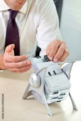 Businessman searching business card from stand